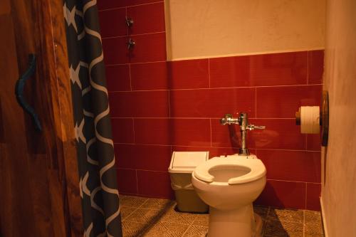 a bathroom with a toilet and red tiles at Coccoloba Guest House in Puerto Escondido