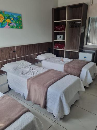 a group of three beds in a room at Miotto Executive Hotel in Navegantes