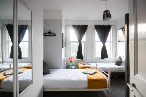 a bedroom with two beds and two windows at Aura - 8ight Havens in Folkestone