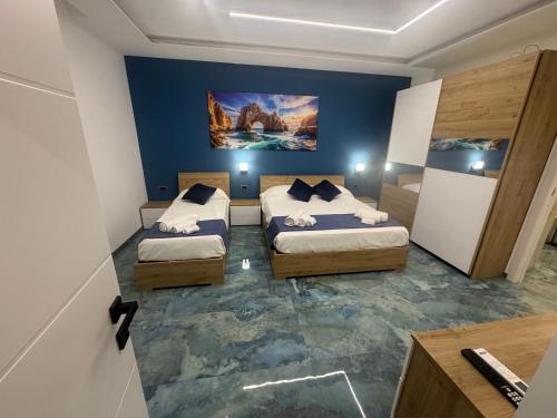 two beds in a room with blue walls and concrete floors at Costa blu in Agropoli