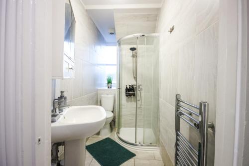 a white bathroom with a sink and a shower at Vibrant - 8ight Havens in Folkestone