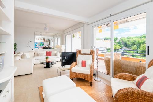 a living room with white furniture and a balcony at Marvista - Bright Apt w Seaview, Pool in Sant Pere de Ribes