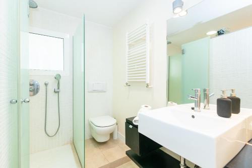 a bathroom with a sink and a toilet and a shower at Marvista - Bright Apt w Seaview, Pool in Sant Pere de Ribes