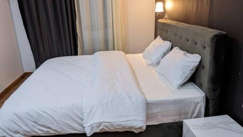 a bed with white sheets and pillows in a room at Mansarda Park View Hotel in Nyagatare
