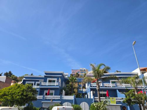 a blue building with palm trees in front of it at lagoon apartment 4 in Moulay Bousselham
