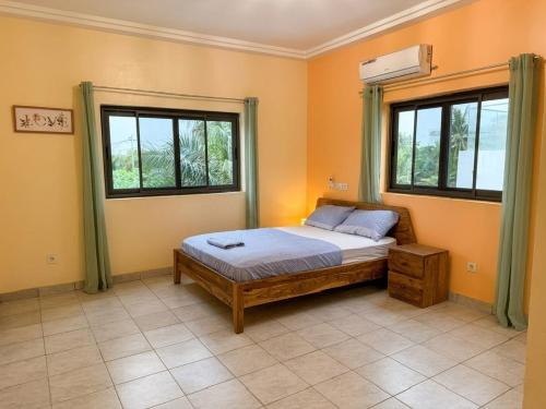 a bedroom with a bed and two windows at Villa Lawsmat avec piscine privée et grand jardin in Lomé