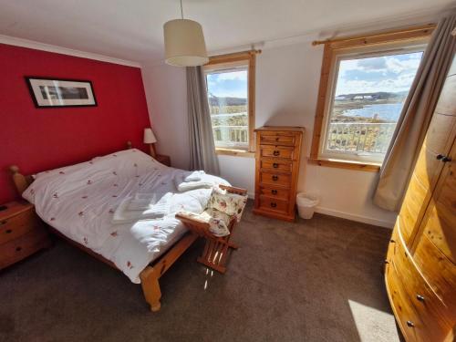 a bedroom with a bed and a dresser and two windows at Lochan View Cottage in Breaclete