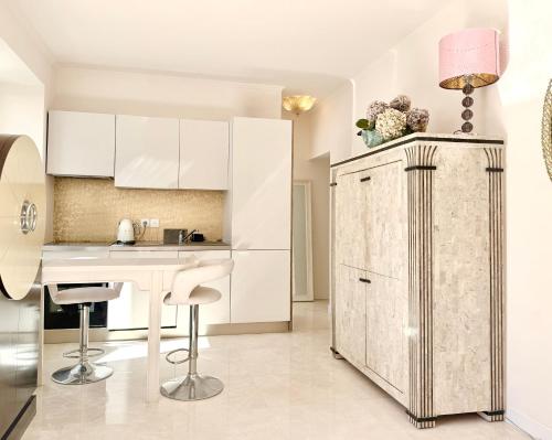 a kitchen with white cabinets and a table and chairs at Monaco 2bdr luxury apartment, private garden&pool in Beausoleil