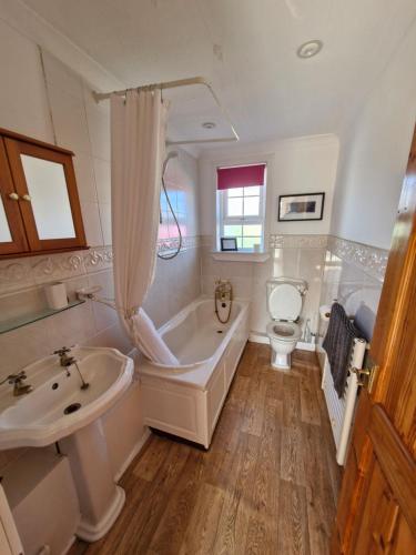 a bathroom with a tub and a sink and a toilet at Lochan View Cottage in Breaclete