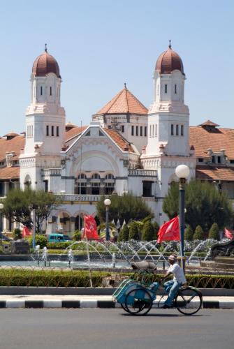 a man riding a bike in front of a building at Hotel Ibis Semarang Simpang Lima in Semarang
