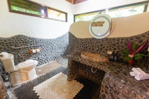 a bathroom with a toilet and a sink with a mirror at La Cusinga Lodge in Uvita