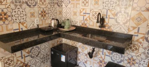 a kitchen with a sink and a tiled wall at Quarto Privativo in Caparaó Velho