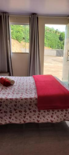 a bedroom with a bed with a red blanket and a window at Quarto Privativo in Caparaó Velho