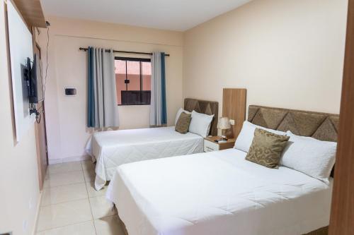 a hotel room with two beds and a couch at New Apart Hotel Ciudad del Este in Ciudad del Este