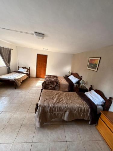 a bedroom with two beds and a tiled floor at HAUS EDELWEISS, Casa Quinta en Monte Grande, Bs As, EZEIZA AIRPORT, GARDEN, SWIMMING POOL in Monte Grande