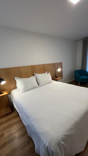 a bedroom with a large white bed and a blue chair at Mercedes Rambla Hotel in Mercedes