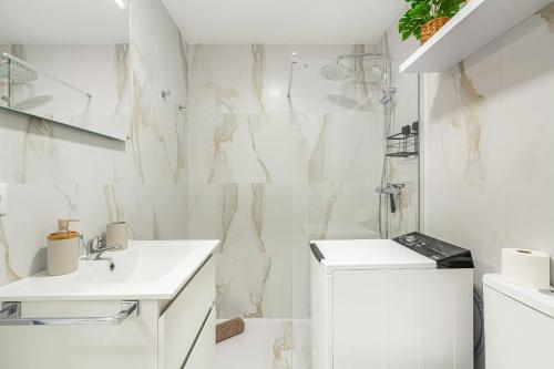 a white bathroom with a sink and a washing machine at Ocean Aura Tenerife in Costa de Adeje
