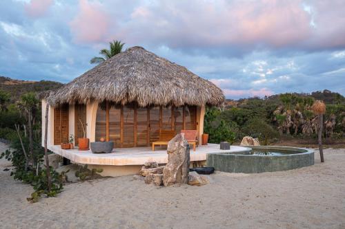a small hut with a thatch roof on a beach at Casa Sal by Tasman in Puerto Escondido