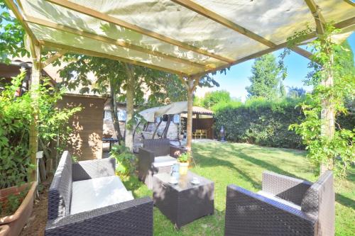 a pergola with chairs and a table in a yard at Casa Guna - Happy Rentals in Asciano