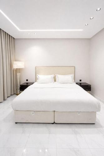 a bedroom with a large white bed with two tables at شقق الياسمين الفندقية in Medina