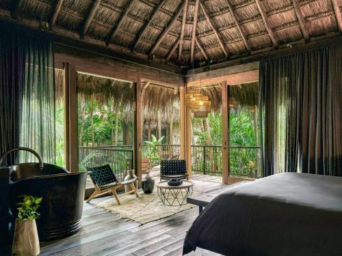 a bedroom with a bed and a balcony with chairs at BE Destination Tulum in Tulum