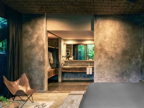 a bedroom with a bed and a bathroom with a mirror at BE Destination Tulum in Tulum