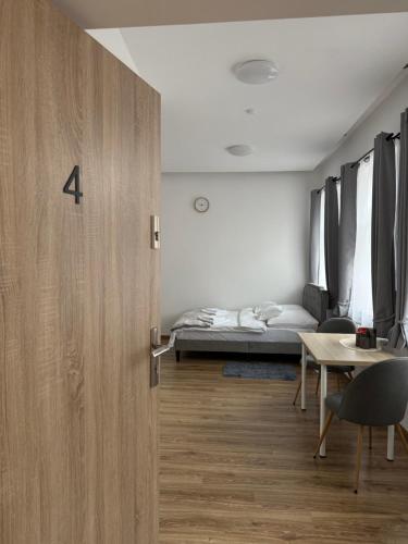 a room with a bed and a door with a table at Apartamenty Stare Podwórko in Pilica