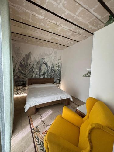 a bedroom with a bed and a yellow couch at Marta House 2 in Trapani