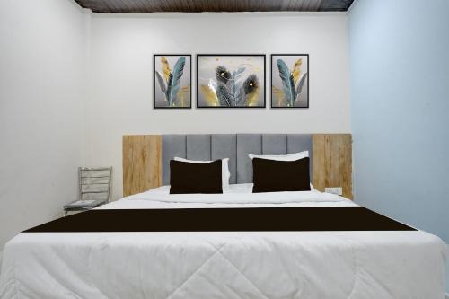 a bedroom with a large bed with four paintings on the wall at Hotel O Viraj Inn in Gwalior