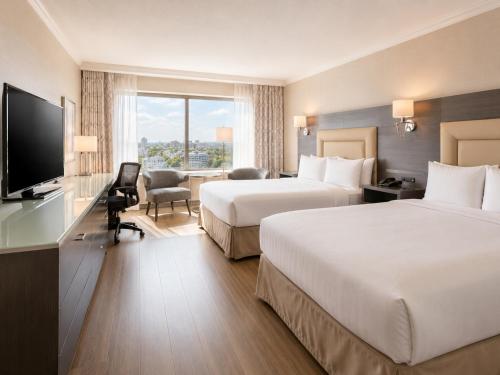 a hotel room with two beds and a flat screen tv at Hôtel Le Concorde Québec in Quebec City