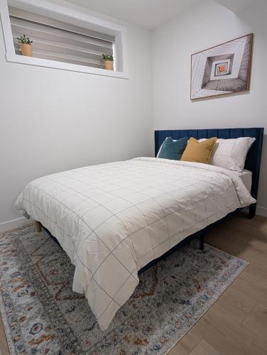 a bed in a bedroom with a blanket on it at Granny's Hug, a cozy 2 Bedroom Basement Suite in Calgary