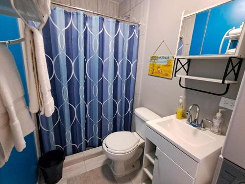 a bathroom with a toilet and a blue shower curtain at Stunning Azul Ocean View Apartment in San Carlos