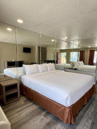 a large bedroom with a large white bed with mirrors at River Inn Motel in San Antonio