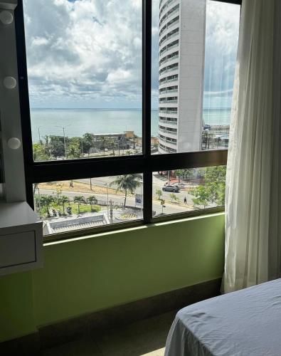 a bedroom with a window with a view of the ocean at Ilusion hotel flat in Natal