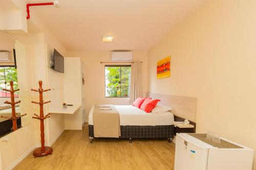 a small room with a bed with red pillows on it at Pousada Vila Taquaras in Balneário Camboriú