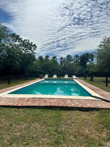 a swimming pool with two chairs in the grass at Habitaciones Casona Las Toscas in Miramar