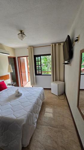 a bedroom with a large white bed and a flat screen tv at Pousada Viking Penedo in Penedo