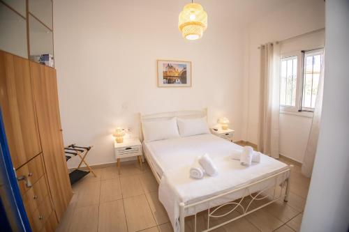 a bedroom with a white bed and two tables at Blue Water Escape in Agioi Theodoroi