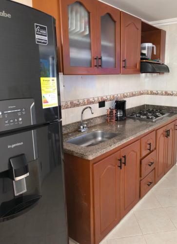 a kitchen with a sink and a black refrigerator at Brisas del Santander in Fusagasuga