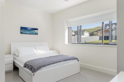 a white bedroom with a bed and a window at Gorgeous Luxury in Lahinch