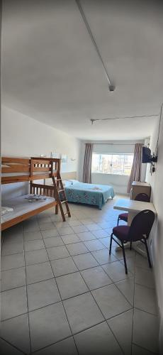a room with two bunk beds and a table and a chair at Hotel Kolman in Capão da Canoa