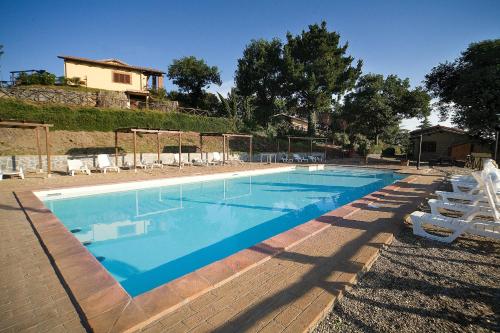 a swimming pool with chairs and a house in the background at AgriResort Spa Glamping Poggio Di Montedoro in Montefiascone