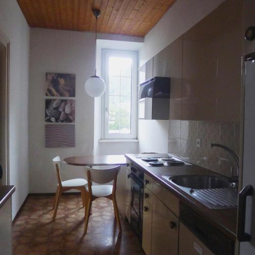 eine Küche mit Tisch und Spüle und Fenster in der Unterkunft Casa Jolanda in Bellinzona