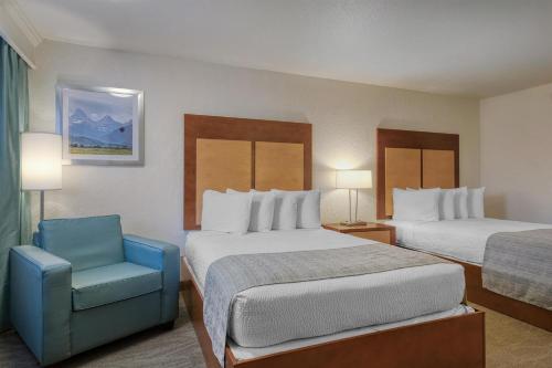 a hotel room with two beds and a blue chair at Best Western Foothills Inn in Mountain Home