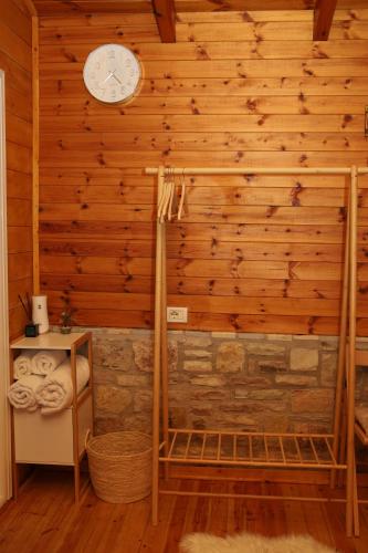 a bathroom with a wooden wall with a clock on the wall at Airport Comfort Nest in Kamëz