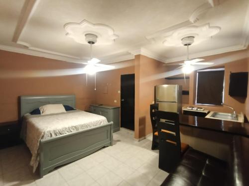 a bedroom with a bed and a desk with a television at Garcias Suites Cuauhtémoc in Linares