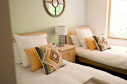 a bedroom with two beds and a mirror on the wall at Kalamunda Estate with Pool, Fire Pit & BBQ Deck in Bundanoon