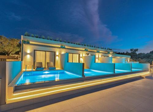 a villa with a swimming pool at night at Helena's Aether Suites - Seaview & Heated Infinity Pool in Tragaki