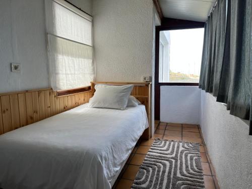 a small bedroom with a bed and a window at Dos Violetas in Mocanal
