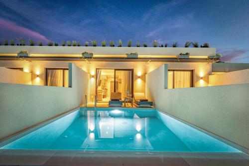 a swimming pool in front of a house at Helena's Aether Suites - Seaview & Heated Infinity Pool in Tragaki